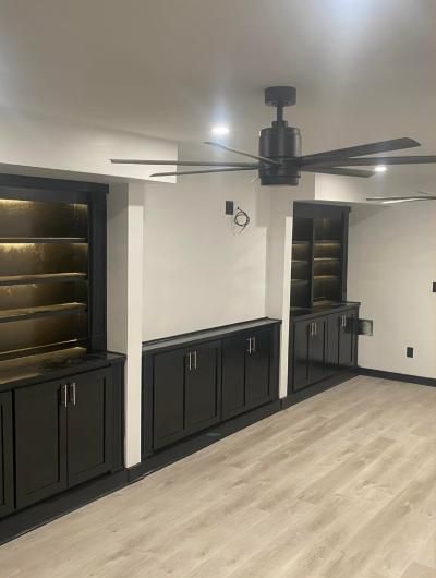 Finished basement remodel with ceiling fan and lit built-in shelving