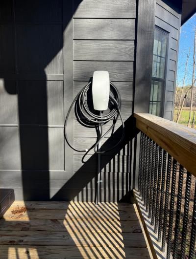 EV charger on a dark exterior wall beside a deck