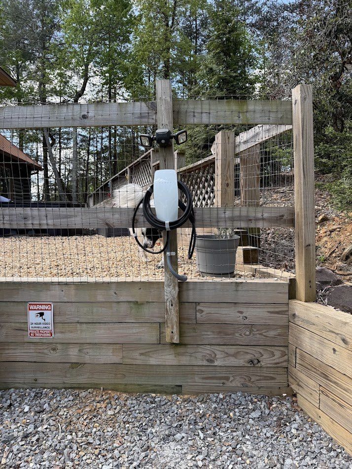 EV charger mounted on a fence post beside a gravel parking pad