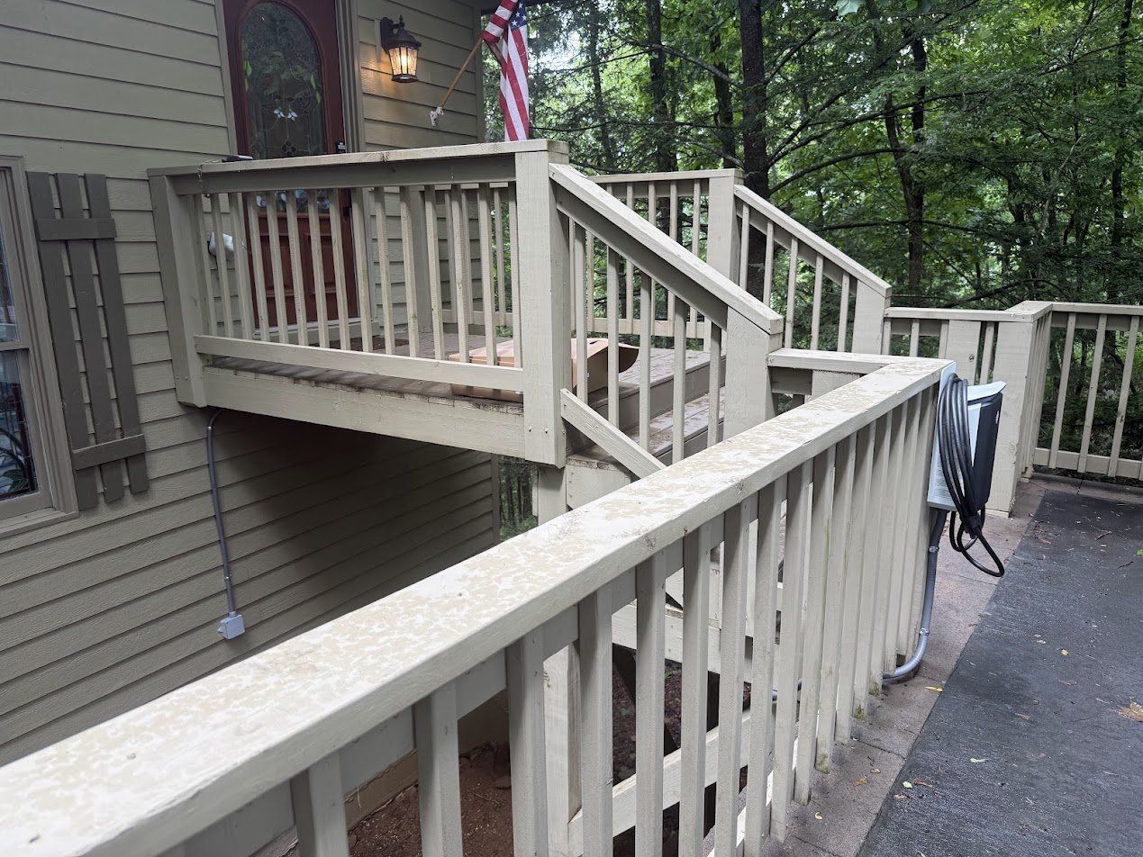 Railing-mounted EV charger with conduit running down the post, beside the front steps