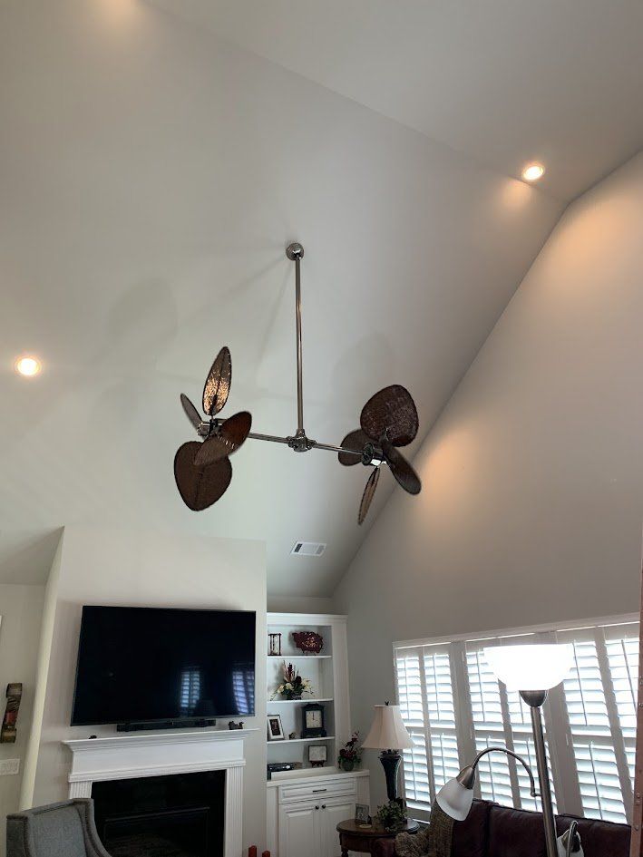 Dual-head ceiling fan with woven palm-leaf blades on a long downrod under a vaulted ceiling