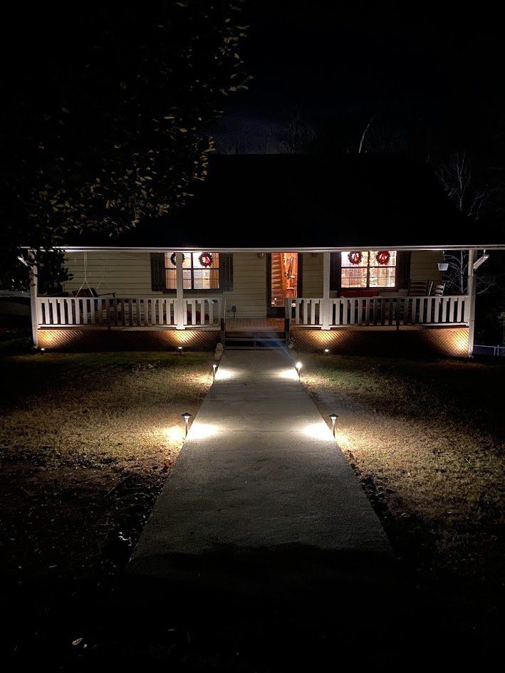 Walkway path lights leading to a porch with under-porch uplighting at night