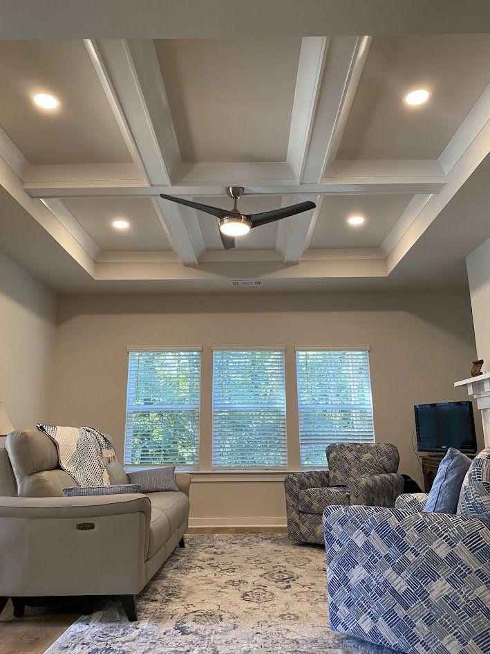 Finished living room with recessed lights and a ceiling fan in the coffered ceiling
