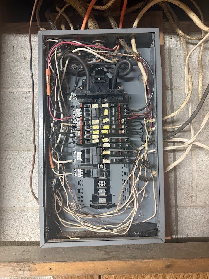 Old crowded electrical panel with tangled wiring
