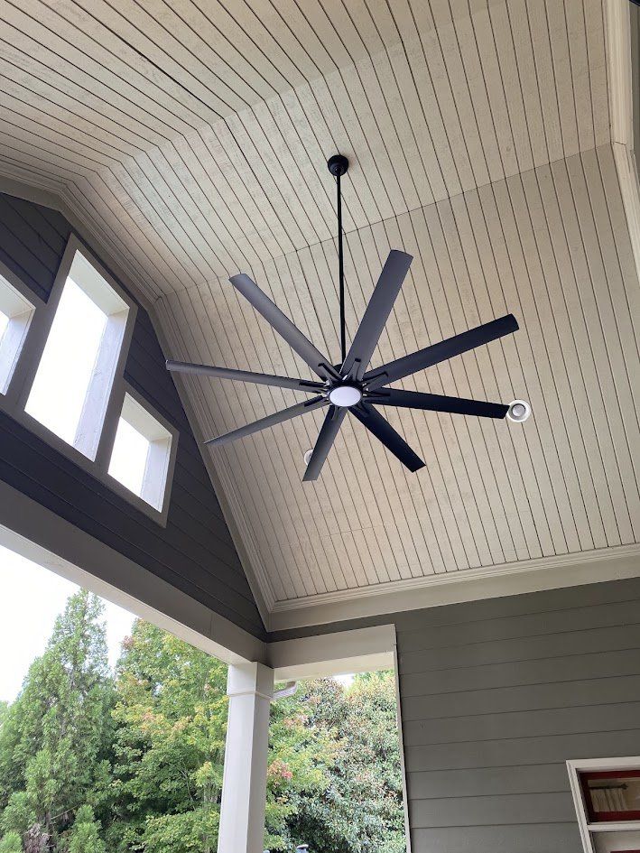 Eight-blade ceiling fan on a downrod under a vaulted porch ceiling