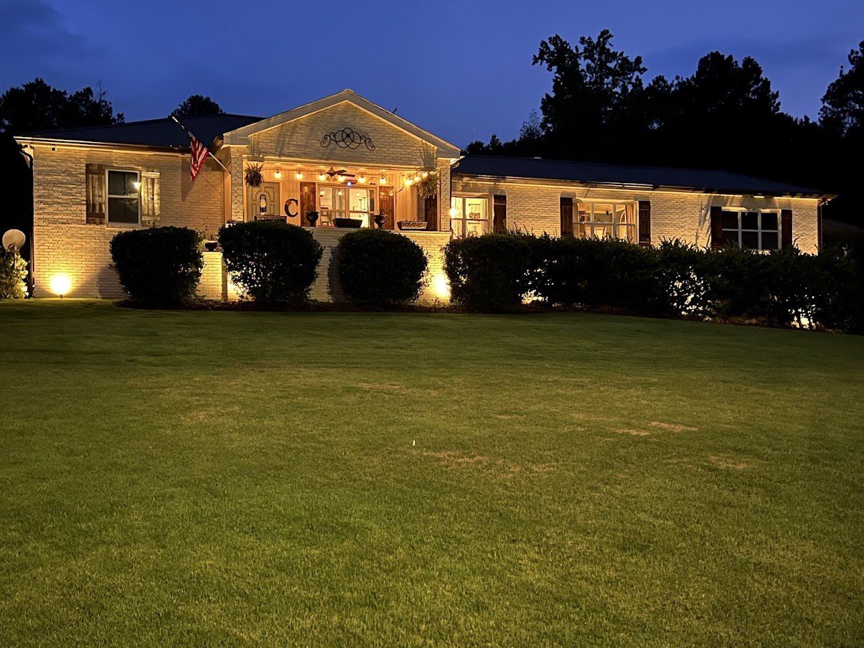 Brick ranch home washed in warm landscape uplighting at dusk