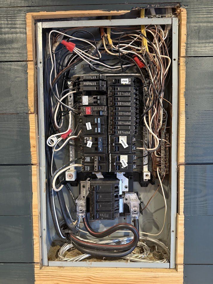 Old overcrowded panel with hand-written breaker labels and tangled wiring